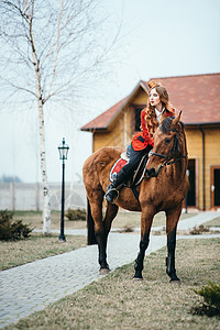 穿红色羊毛衣和黑高靴子的红头发骑马女孩季节森林旅行骑士训练运动天空阴影骑术棕色背景图片