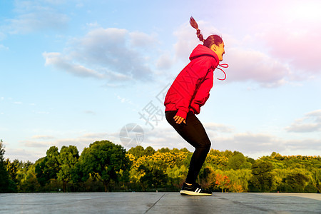 快乐的年轻女孩跳过花园 在太阳光下自由阳光天空女性日落女士活力蓝色乐趣跳跃图片