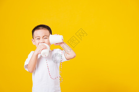 小男孩微笑 站着如此快乐的打纸手艺童年耳朵电缆白色男孩们注意力黄色孩子工作室电话图片