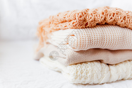 白色背景的蜜蜂羊毛衣皮 暖编织的毛衣和围巾叠成一堆图片