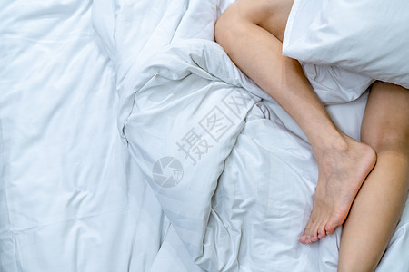 妇女赤脚躺在白毯子和床边的床上图片
