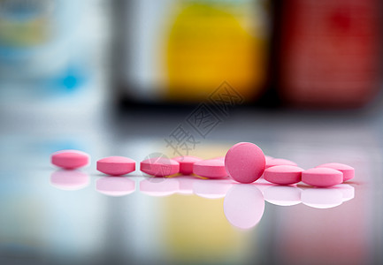 药物中药瓶模糊背景下的粉红色药丸图片