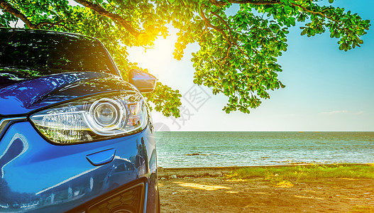 蓝色运动SUV车停在热带海边的雨伞塔下海滩气氛杂交种树叶驾驶奢华旅行岩石海岸太阳图片