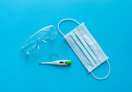 医用防护面罩 温度计和防护眼镜位于蓝色背景上 针对 covid19 的防病毒保护套件 2019 冠状病毒大流行凝胶医院诊所手套消图片