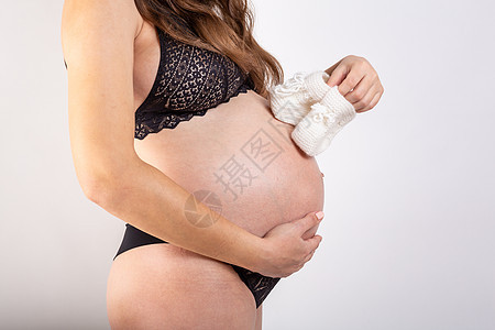 幸福的孕妇手里拿着蓝色婴儿鞋 妈妈怀孕了 孕妇腹部 怀孕婴儿成人母亲女性女士衣服身体父母生活女孩图片