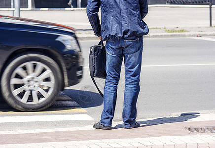 在行人交叉路口和汽车交通中等待男子图片