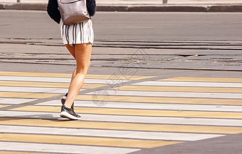 年轻妇女的双腿跨过城市街道图片