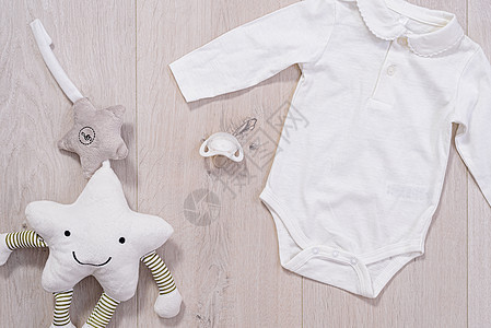 婴儿服装概念 男女孩白西装和木制背景婴儿奶嘴罩;图片
