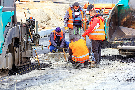 戴保护面罩的公路工人工作组为道路新路段必要的沥青铺设了必要程度的柏油布线水平图片