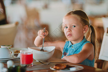 可爱的小女孩在户外咖啡厅吃早餐小吃橙子餐厅金发快乐水果孩子瓶子婴儿女儿图片