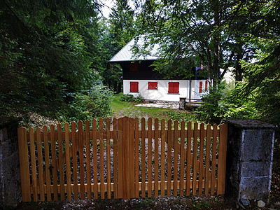 附近围栏后面有红色窗帘的美丽小屋图片
