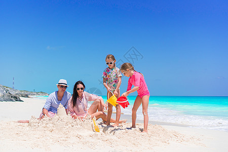 四个家庭在热带白沙滩建沙丘城堡玩具父亲情调男人海岸海洋乐趣喜悦支撑游泳衣图片