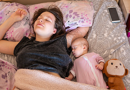 年轻母亲和她的孩子睡在床上图片