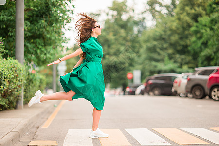 穿着绿色衣服的年轻女子在城市散步女性女孩首都魅力裙子发型街道季节皮肤日落图片