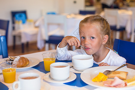 可爱的小女孩在餐厅吃早餐了婴儿酒店女性快乐女儿假期桌子咖啡店童年孩子图片