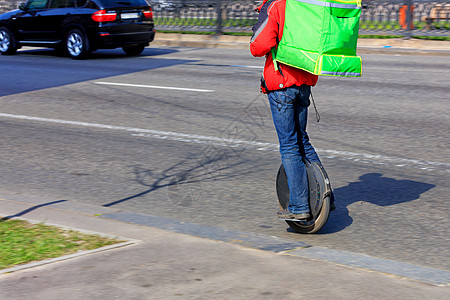 一个携带异地热绿色背包的快递员 背在一辆带食品的单轮电动车上图片