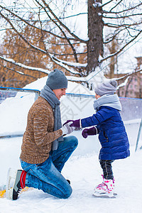 可爱的小女孩和快乐的父亲 在户外滑冰溜冰小姑娘家庭婴儿娱乐闲暇教学男性训练生活方式孩子图片