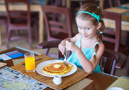 可爱的小女孩在户外咖啡厅吃早餐快乐餐厅橙子女孩桌子蜂蜜西瓜小吃金发果汁图片