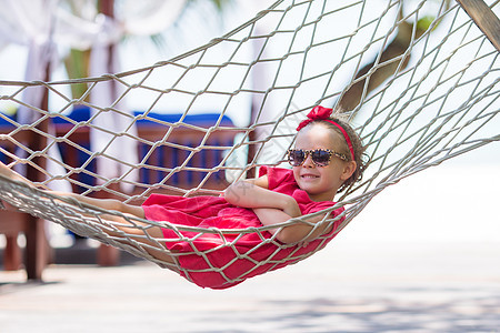 热带度假时可爱的小女孩 在吊吊吊床上放松吊床海岸乐趣游客假期棕榈喜悦闲暇情感孩子图片