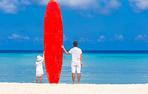 暑假期间带冲浪滑板的小女孩和年青父亲图片
