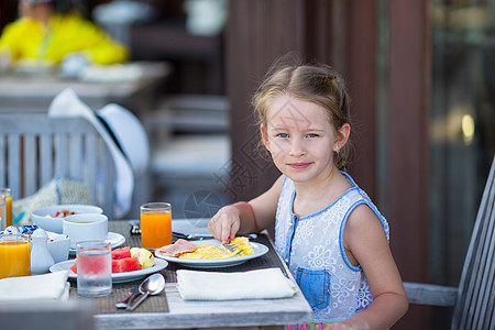 可爱的小女孩在户外咖啡厅吃早餐橙子西瓜水果眼睛孩子咖啡店食物假期女儿蜂蜜图片