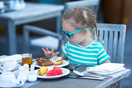 可爱的小女孩在户外咖啡厅吃早餐西瓜蜂蜜瓶子食物橙子孩子快乐假期桌子小吃图片