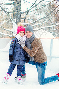 可爱的小女孩和快乐的父亲 在户外溜冰场上帮助学习小姑娘女儿家庭滑冰溜冰者娱乐闲暇孩子图片
