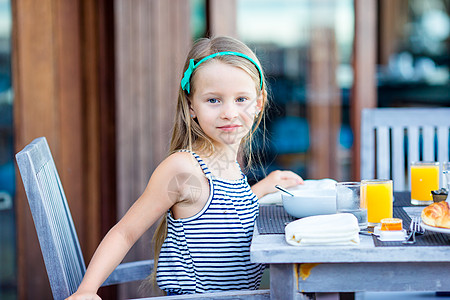 可爱的小女孩在户外咖啡厅吃早餐水果咖啡店眼睛小吃女儿快乐餐厅桌子瓶子杯子图片