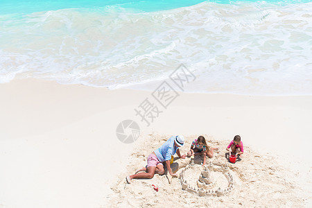 从上到下 父亲和小女儿在热带海滩建沙城堡图片