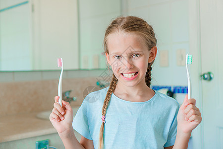 小笑脸女孩在洗手间刷牙幸福牙膏药品喜悦孩子瞳孔打扫青年浴室牙刷图片