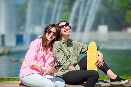 欧洲城市的年轻城市女孩快乐 高加索女人一起在户外玩得尽兴旅游滑冰指导太阳镜女士街道微笑成人公园相机图片