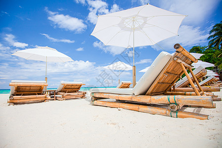 外来热带白色沙沙滩上的海滩床和白色雨伞背景