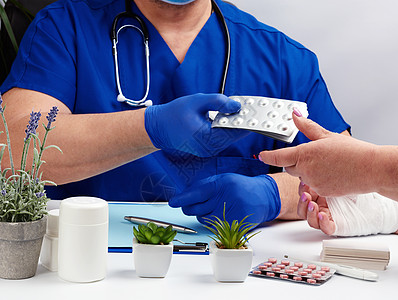 穿着制服和蓝色乳胶医用手套的医生坐在桌子旁绷带卫生情况手指包扎考试医师创伤保健拇指图片
