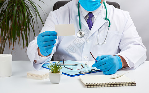 身穿白色医疗大衣的医生坐在棕色礼服的桌子上卡片工作外套医师药品展示广告男人蓝色临床图片