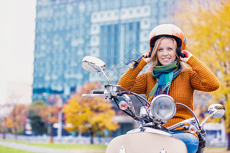 成年美女的肖像 戴上头盔在公园骑摩托车时戴头盔畅销书姿势骑术树木驾驶微笑衣服安全下载围巾图片