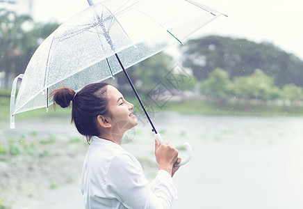 带着伞女孩雨季时 带着雨伞 微笑和快乐的近身妇女女士乐趣幸福享受风暴女孩女性喜悦成人阳伞背景