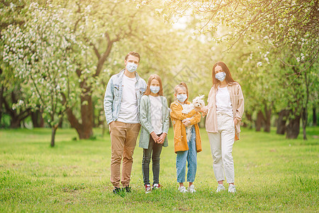 在盛开的樱花花园中戴面罩的可爱家庭细菌女孩感染疾病女儿自由父亲公园面具孩子图片