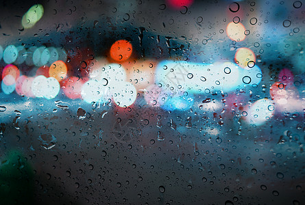 道路雨季背景下带光散景的雨滴图片