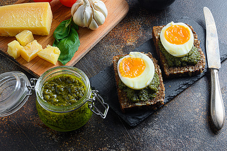 自制鸡蛋帕尼尼面包配绿色罗勒香蒜酱在玻璃瓶中 意大利早餐银勺配料绿色香蒜酱在 gmetal 桌面上特写图片