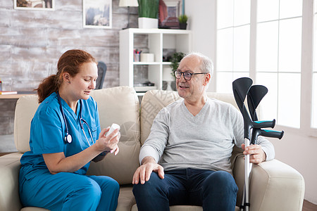 女护理员告诉在养老院带拐杖的快乐老年男子护理女士成人保健照顾者疾病帮助护士医疗药品图片