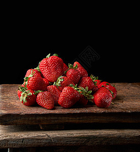 木桌上的一串新鲜的成熟红草莓甜点浆果水果黑色桌子衬套叶子食物收成红色图片