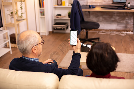 老年退休夫妇的后视镜 看着一个带白色隔离屏幕的智能手机小样技术丈夫男人互联网女士阅读微笑快乐老年人图片