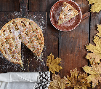烤圆苹果馅饼和盘子上一块切片馅饼午餐桌子木头糕点美食小吃水果甜点面包图片
