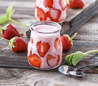 成熟的红色草莓和两罐玻璃冰淇淋图片