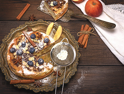 烤圆苹果派和含糖粉的铁筛子传统美食糕点棕色桌子午餐甜点浆果脆皮食物图片