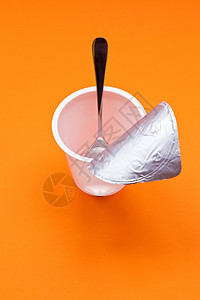 橙色背景的勺子空清酸奶杯薄片早餐塑料牛奶厨房橙子食物奶油饮食奶制品图片