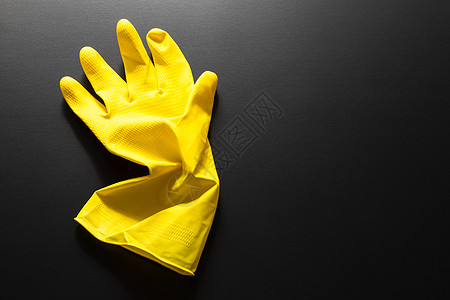 在黑色背景上隔离的黄色橡胶手套用具橡皮打扫手指图片