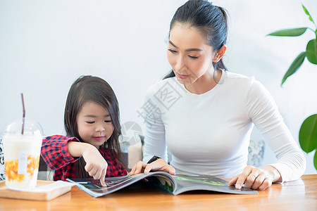 亚裔母亲正在教女儿在T期间读一本书孩子沙发幸福父亲阅读作业家庭快乐学校学习图片