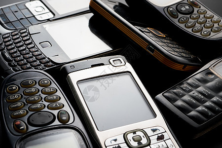 黑色背景中的旧手机和过时手机金属电子讲话细胞电话垃圾工具纽扣收藏数字图片