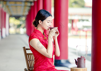 穿旧中国传统服装的亚洲美女 喝水i裙子旅行杯子旗袍女士大厅戏服情感宗教茶壶背景图片